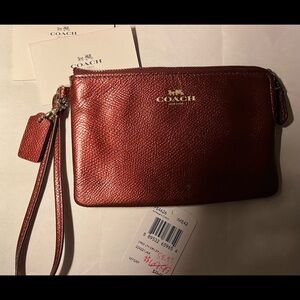 Red metallic Coach wristlet with zipper closure + bag tag attached